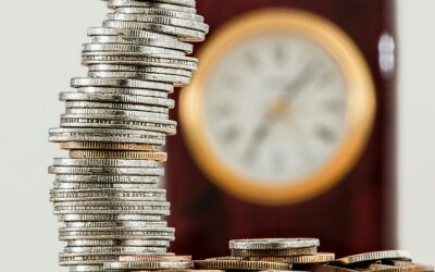 Inversión a largo plazo frente a corto plazo: pros y contras A close-up image of stacked coins with a blurred clock, symbolizing time and money relationship.