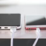 Two smartphones charging side by side on a desk. Modern and technological setting.