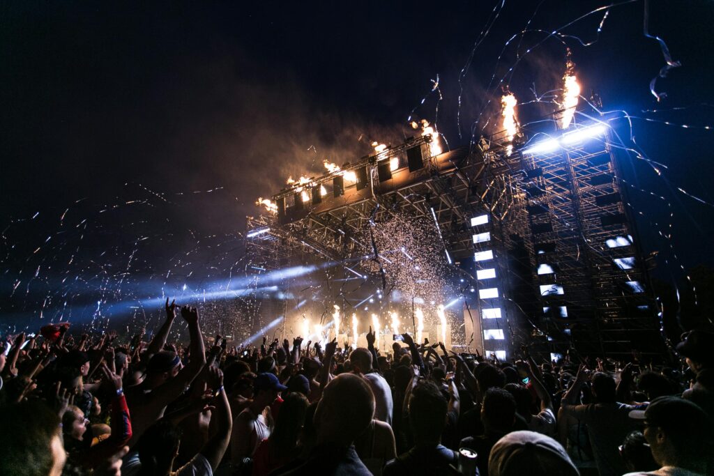 Escena de conciertos vibrantes con multitud disfrutando de festivales nocturnos y fuegos artificiales de escenario dinámicos.