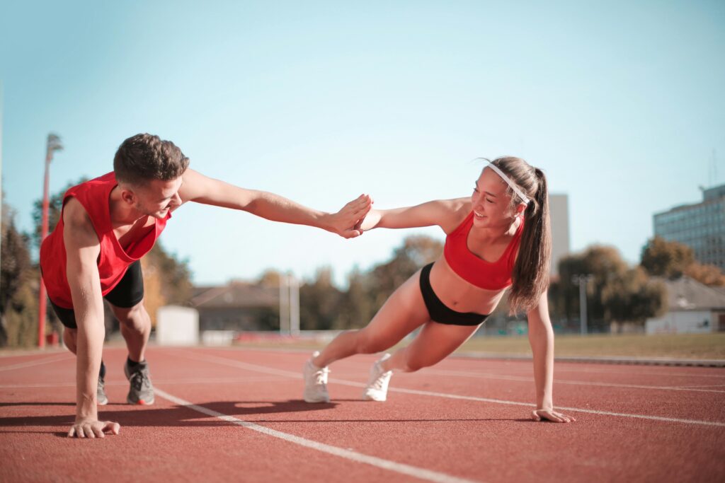 Entrenamiento al aire libre con un hombre y una mujer que participan en una tabla de chocar los cinco en una pista.
