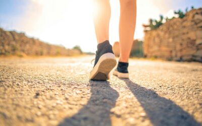 A woman walks down a sunlit path in summer, highlighting leisure and travel outdoors.