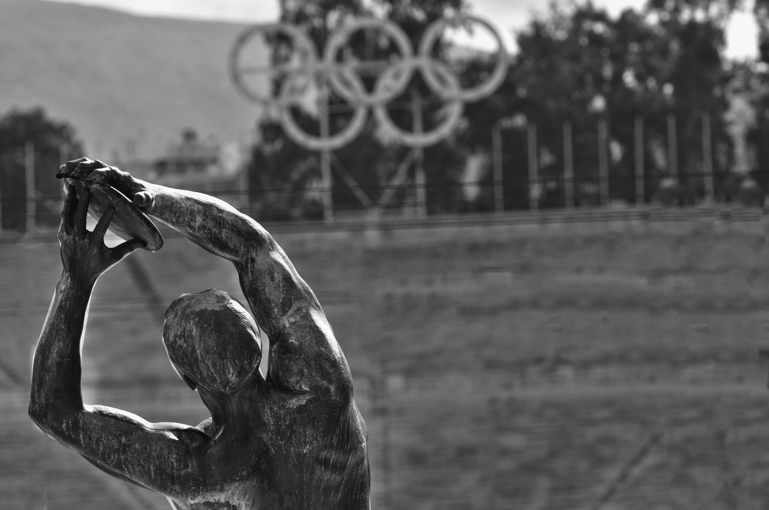 Black and white photo of a statue with Olympic rings in Panathenaic Stadium, Athens.